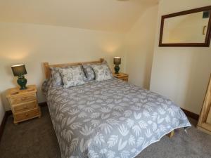 a bedroom with a bed and two night stands with lamps at Avoine Cottage in Gloucester