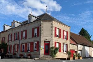 an old building with red shutters on a street at Gite Au Fil de lEau 
