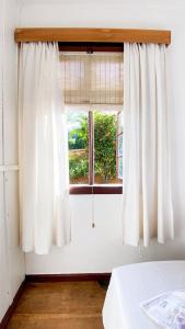 a window with white curtains in a room at Pousada Casa Wachholz - Rota do Enxaimel in Pomerode