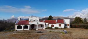 une maison blanche avec un toit rouge et des montagnes en arrière-plan dans l'établissement Casa Tafi del Valle, à Tafí del Valle