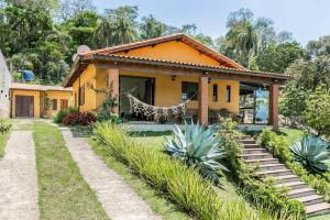 una casa amarilla con un jardín delante de ella en Sítio a 60KM de SP - 5 Quartos - Piscina Aquecida, en Ibiúna