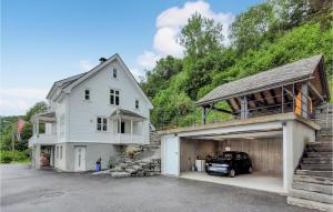 a white house and a garage with a car in it at Stunning Home In ystese With Wifi And 4 Bedrooms in Øystese