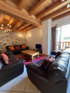 een woonkamer met 2 leren banken en een tafel bij The Stable House Bourg d’Oisans -bike/hike/ski in Le Bourg-dʼOisans