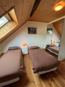 2 bedden in een zolderslaapkamer met houten plafonds bij The Stable House Bourg d’Oisans -bike/hike/ski in Le Bourg-dʼOisans