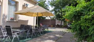 a table and chairs with an umbrella in front of a building at Megyeház Apartman in Makó