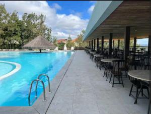 格雷夫森德的住宿－FLAT NA FAZENDA MONTE CASTELO GRAVATÁ - Pe，一座带桌椅的游泳池位于酒店大楼旁