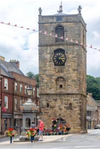 a stone clock tower with a clock on it at The Cranny 2 Bed House in Central Morpeth in Morpeth