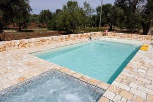 a swimming pool with a stone wall around it at trullo nonna netta con piscina idromassaggio e area giochi in Ceglie Messapica