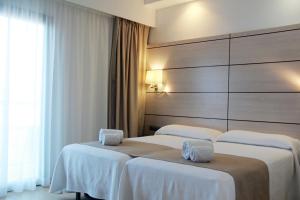 2 Betten in einem Hotelzimmer mit weißer Bettwäsche in der Unterkunft Hotel Puchet in Sant Antoni de Portmany