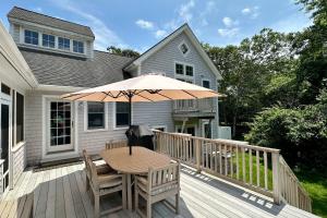 a wooden deck with a table and an umbrella at Edgartown Retreat in Edgartown