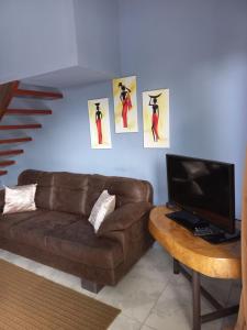 un salon avec un canapé brun et une télévision dans l'établissement Casa Hortensia, à Nicoya
