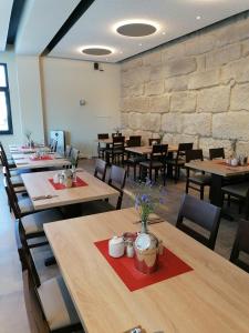 comedor con mesas y sillas y pared de piedra en Landgasthof Niebler, en Adelsdorf