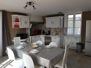 une cuisine avec une table, des placards blancs et des chaises blanches dans l'établissement Maison tout confort pour 4 à 6 dans village paisible, à Argenteuil-sur-Armançon