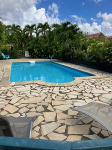 una piscina con una pasarela de piedra alrededor en La Kallina, en Grand-Bourg