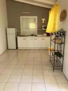 uma cozinha com um frigorífico e piso em azulejo em La Kallina em Grand-Bourg