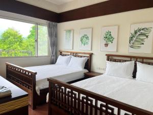 Duas camas num quarto com uma janela em 杉羽松民宿 Seeing A Song INN em Luodong