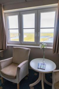 a room with a table and chairs and windows at Anker's Hörn - Hotel & Restaurant auf der Hallig Langeness in Langeneß