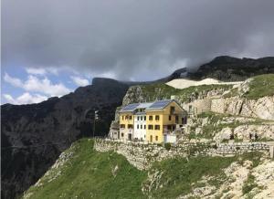 a yellow house on the side of a mountain at CASALIDIA monolocale in Valli del Pasubio