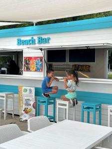 Ein Mann und ein kleines Mädchen sitzen in einer Bar in der Unterkunft Hotel Marina Port in Balatonkenese