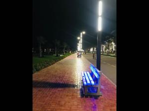 a blue bench sitting on a brick sidewalk at night at Porto Said Resort Rentals in Port Said