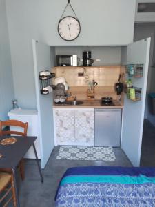 una pequeña cocina con fregadero y un reloj en la pared en Studio Grand Hôtel, en Capvern