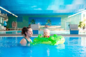 a woman and a baby in a swimming pool at AHORN Berghotel Friedrichroda in Friedrichroda