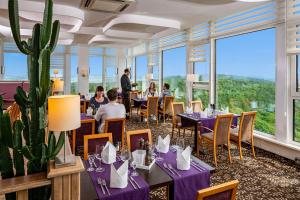 フリードリッヒローダにあるAHORN Berghotel Friedrichrodaの紫のテーブルと椅子、サボテンのあるレストラン
