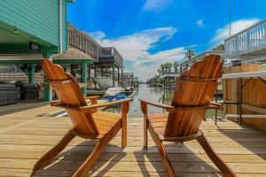 two wooden chairs sitting on a dock next to a river at Jamaican Waves in Galveston