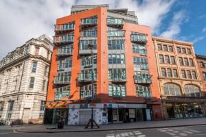 a tall orange building on the corner of a street at The Works-Fresh 2bed in centre, opposite Arndale. in Manchester