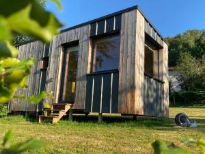 a wooden tiny house with large windows in a field at L’Escargoterie de la Forge - Immersion Champêtre in Uzemain