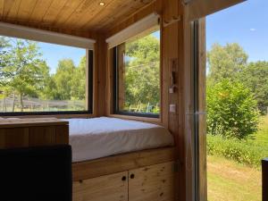 a bed in a tiny house with two windows at L’Escargoterie de la Forge - Immersion Champêtre in Uzemain