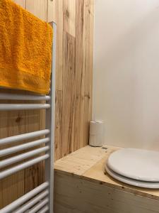 La salle de bains est pourvue de toilettes et d'un mur en bois. dans l'établissement L’Escargoterie de la Forge - Immersion Champêtre, à Uzemain
