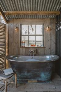 eine große Badewanne in einem Zimmer mit Fenster in der Unterkunft Outbuildings Dorset in Bridport