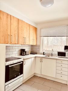 cocina blanca con armarios blancos y ventana en Lovely 2-bed Flat In Stockholm, en Sollentuna