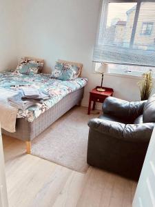 a bedroom with a bed and a couch and a window at Lovely 2-bed Flat In Stockholm in Sollentuna