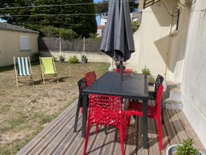 a black table with red chairs and an umbrella at Les Sables d'or in Agon Coutainville +18 photos