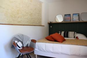 a bedroom with a bed and a chair and a painting at Gîte de la Forge, le Grenier in Fléré-la-Rivière