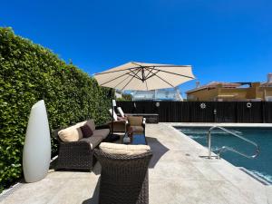 a patio with an umbrella and chairs next to a pool at Villa Sam in Murcia