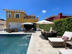 a pool with chairs and umbrellas next to a house at Villa Sam in Murcia