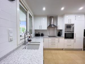 a kitchen with white cabinets and a sink at Villa Sam in Murcia