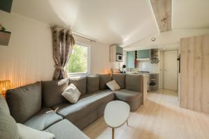 Una sala de estar con un sofá y una cocina. en Mobil Home les pieds dans l'eau, en Canet-en-Roussillon