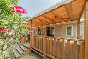una casa con terraza de madera con pérgola en Mobil Home les pieds dans l'eau, en Canet-en-Roussillon