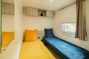 Dos camas en una habitación pequeña con ventana. en Mobil Home les pieds dans l'eau, en Canet-en-Roussillon 16 fotos más