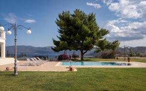 einen Pool mit einem Baum, Stühlen und einer Lampe in der Unterkunft Villa Fantasia Isthmia in Isthmia