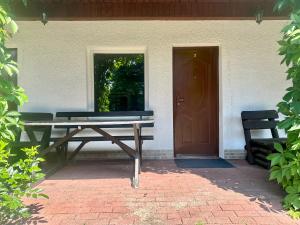 a wooden bench sitting outside of a house with a door at Leniwy Kot in Stegna