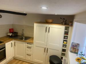 a kitchen with white cabinets and a sink at Grade Two Listed Cosy Cottage 