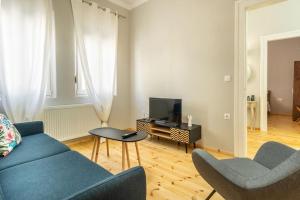 a living room with a blue couch and a tv at Evergreen mansion in Alexandroupoli