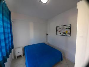 1 dormitorio con 1 cama azul en una habitación blanca en Condomínio Elisabetta 1, en Arraial do Cabo