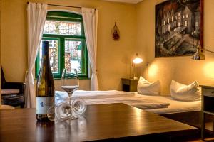 Una habitación con una botella de vino en una mesa con una cama en Pension Rauschenstein, en Bad Schandau