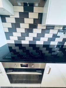 a kitchen with black and white tile on the wall at Deluxe 2 Bedroom Apartment in Sheffield